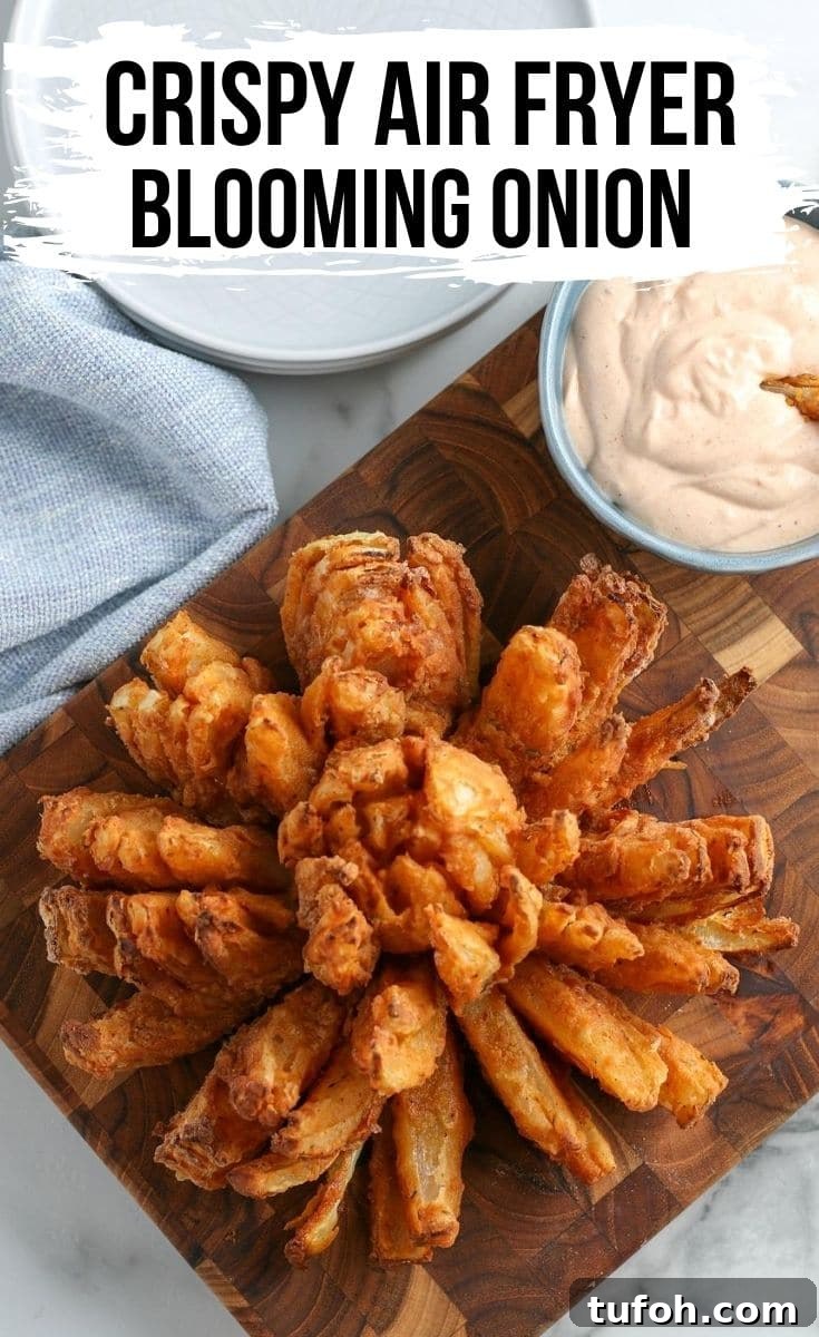 Crispy Air Fryer Bloomin' Onion Recipe for Game Day 2 blooming onion on a wood cutting board with dipping sauce in the background.