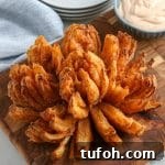 Crispy Air Fryer Bloomin' Onion Recipe for Game Day 13 crispy air fryer blooming onion on a wood cutting board.