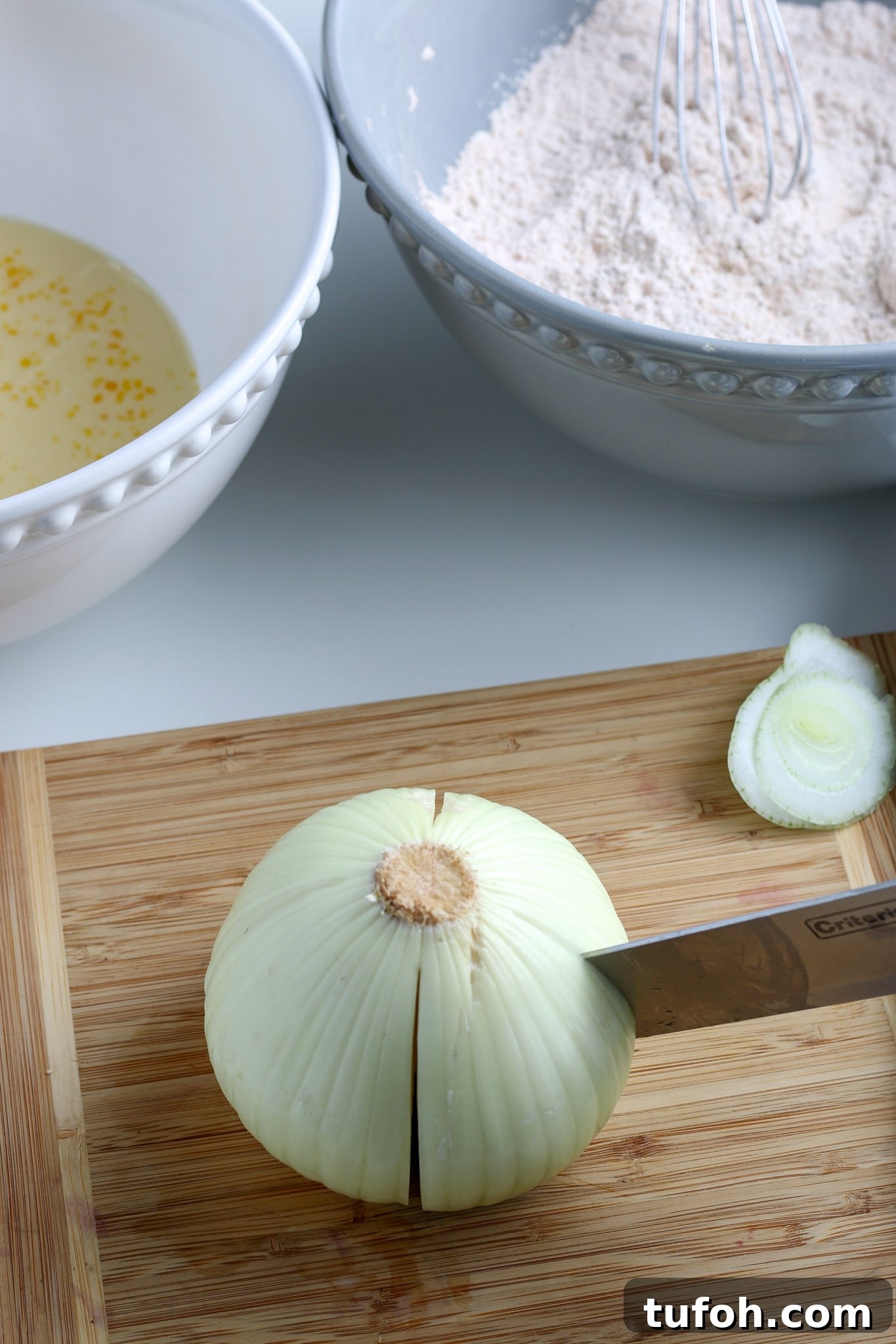 Crispy Air Fryer Bloomin' Onion Recipe for Game Day 5 the onion being quartered on a wooden cutting board.