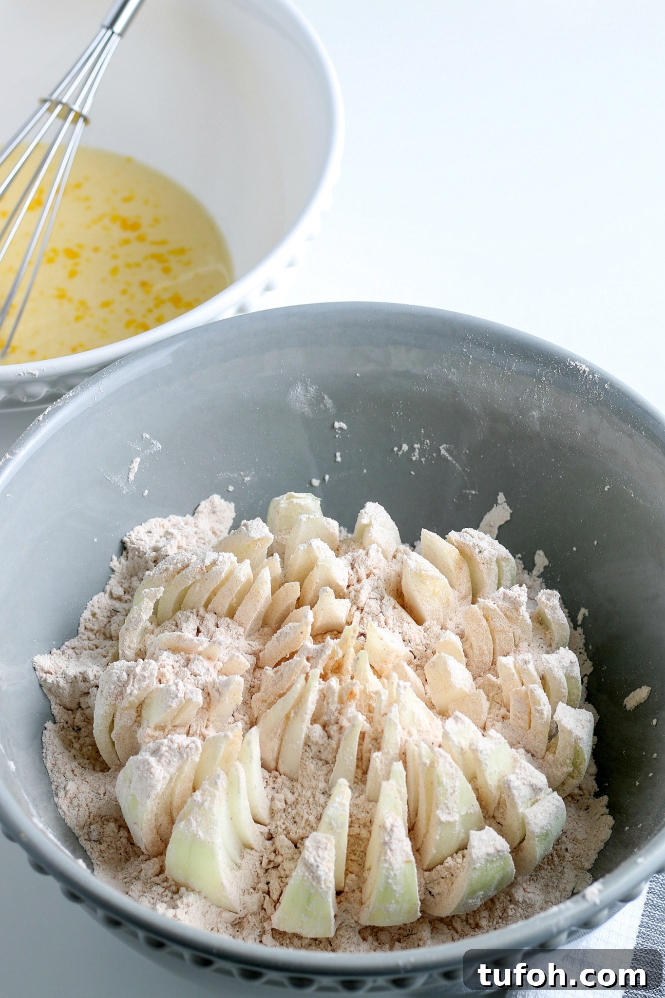 Crispy Air Fryer Bloomin' Onion Recipe for Game Day 10 a raw onion being dredged in flour.
