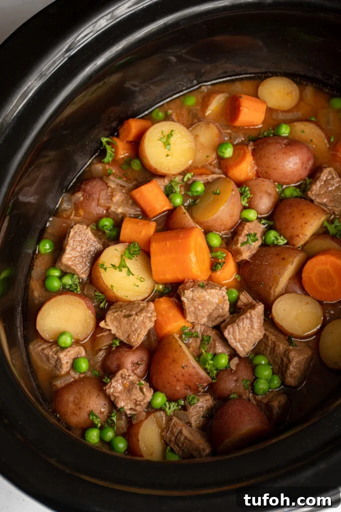 Slow-Cooker Beef Stew with Tender Chunks and Veggies 2 Crockpot full of beef stew filled with carrots, potatoes, chuck roast, and peas.