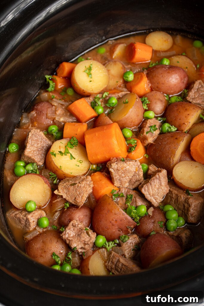 Slow-Cooker Beef Stew with Tender Chunks and Veggies 6 A slow cooker filled with beef stew with carrots, potatoes, peas, and beef.