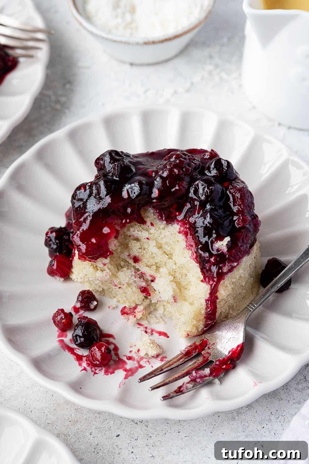 Vegan Berry & Coconut Steamed Puddings Recipe 3 Close up of a steamed berry and cocconut pudding with a forkful removed.