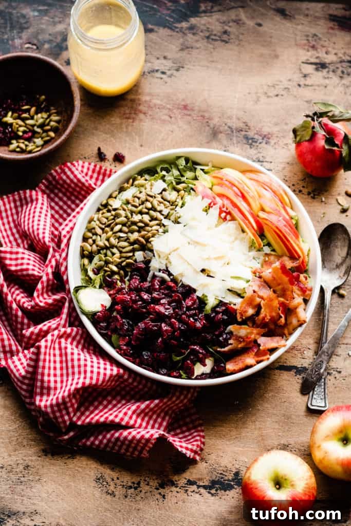 A bowl of all the salad ingredients, before being tossed, on a wooden surface with a red and white checked linen