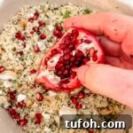 A pomegranate being held over the couscous dish