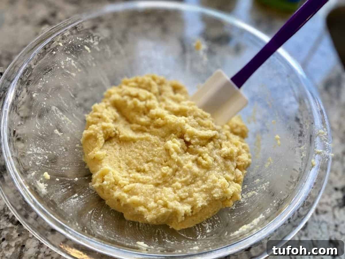 Vegan cornbread mix in a bowl with a spoon on the counter.