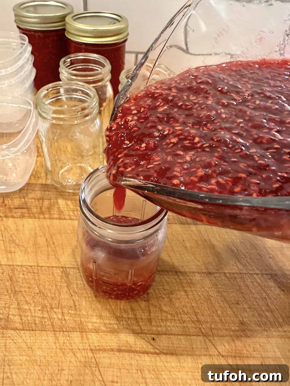 No-Cook Raspberry Jam Without Pectin or Canning 9 A small jar being filled with raspberry jam.