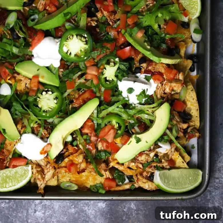 These sheet pan loaded chicken nachos are delicious AND easy to make! Make the slow cooker chicken the night before or the morning of to save time. This appetizer is the perfect game day food and it's also great for large holiday gatherings