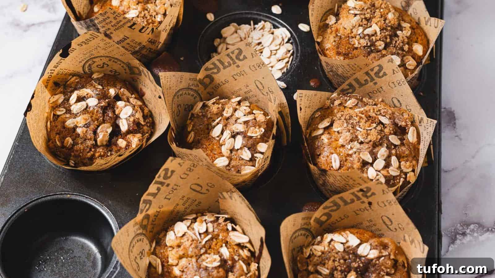21 Kid-Friendly Treats to Make Together (Simple Recipes) 19 A close-up of a muffin topped with oats, resting on crumpled brown paper with printed text. The muffin is set on a marble surface.