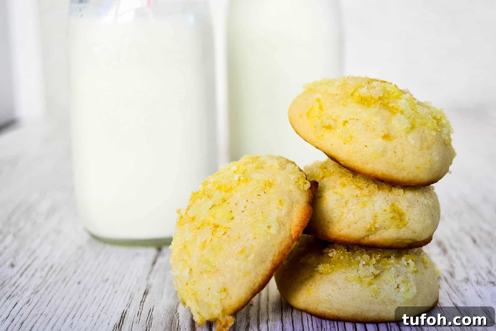 21 Kid-Friendly Treats to Make Together (Simple Recipes) 10 A stack of three lemon sugar cookies with one cookie leaning against the stack, in front of jars of milk.