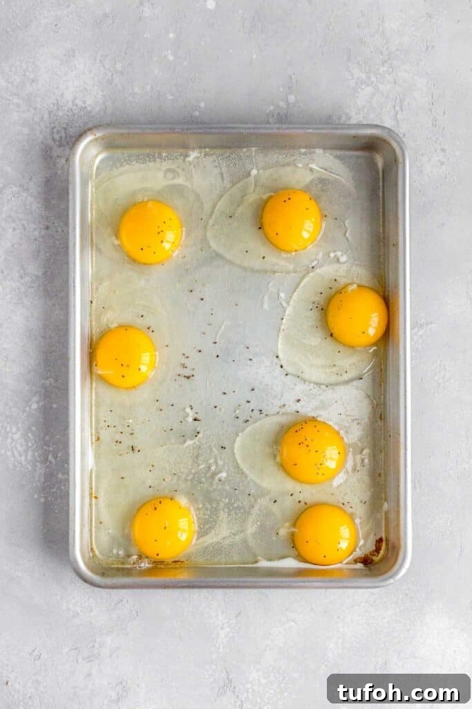 Eggs added to a sheet pan and seasoned with salt and pepper.