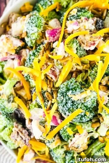A serving bowl full of broccoli crunch salad garnished with shredded cheese.