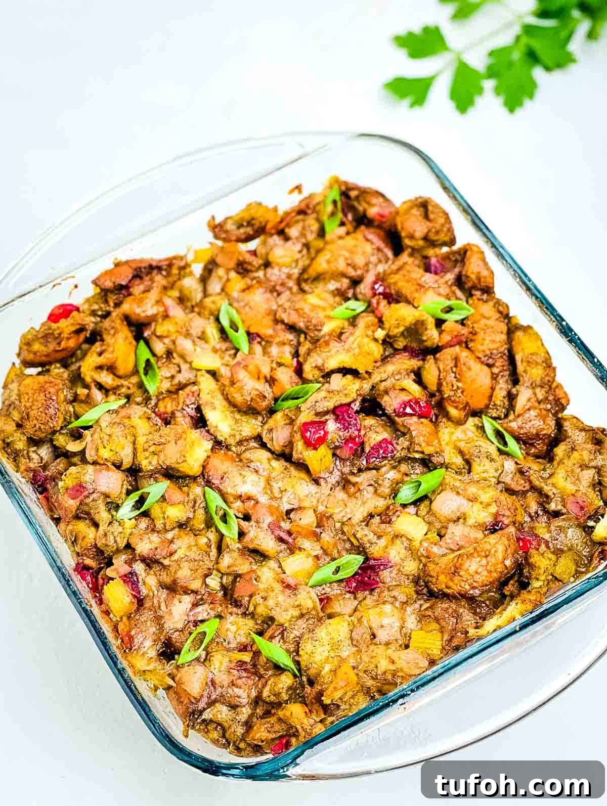 Savory Bacon and Cranberry Stuffing Recipe for Holidays 7 The crispy homemade stuffing in a glass baking dish, garnished with diced green onion.
