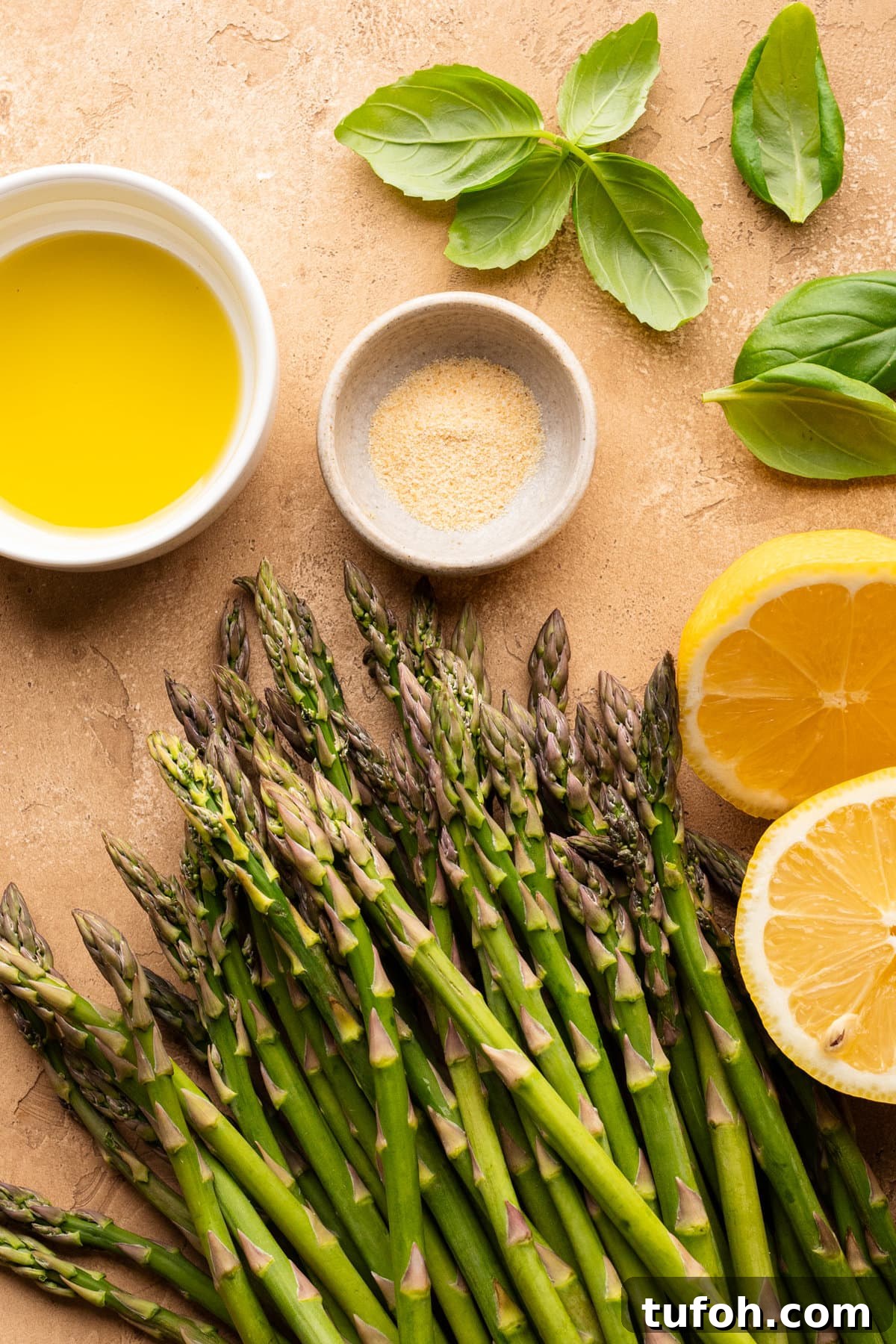 Ingredients for lemon asparagus with basil arranged on a tan background.