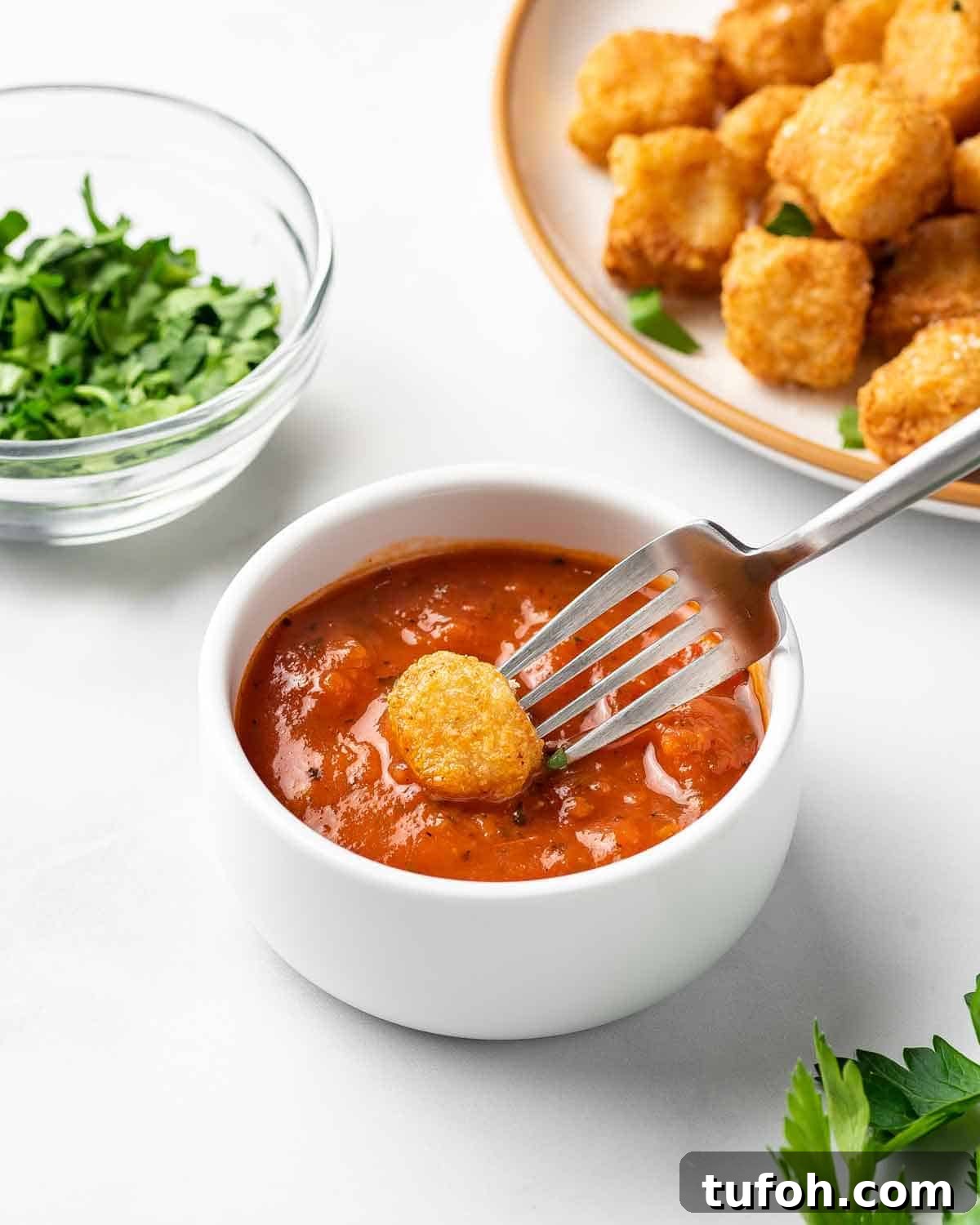 An air fryer cauliflower gnocchi dipped in marinara sauce.