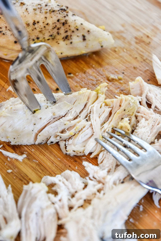 shredding chicken on a cutting board.