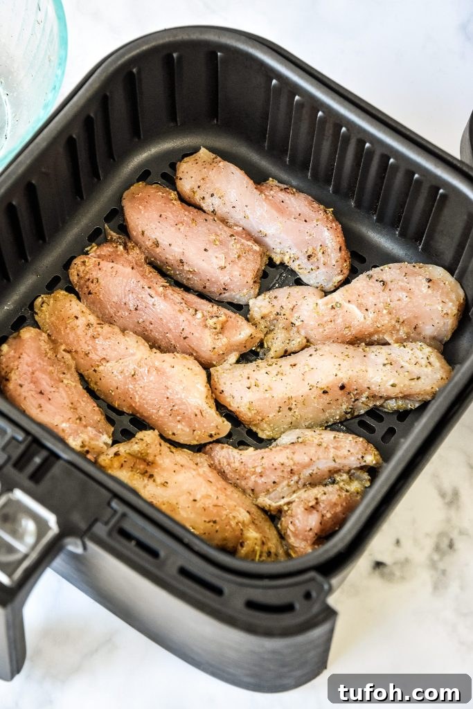 raw marinated chicken in the air fryer basket about to be cooked.