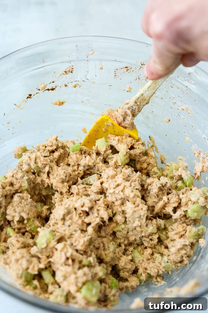 Citrus-Dill Salmon Salad with Avocado and Mixed Greens 5 stirring salmon with the rest of the ingredients in a glass bowl