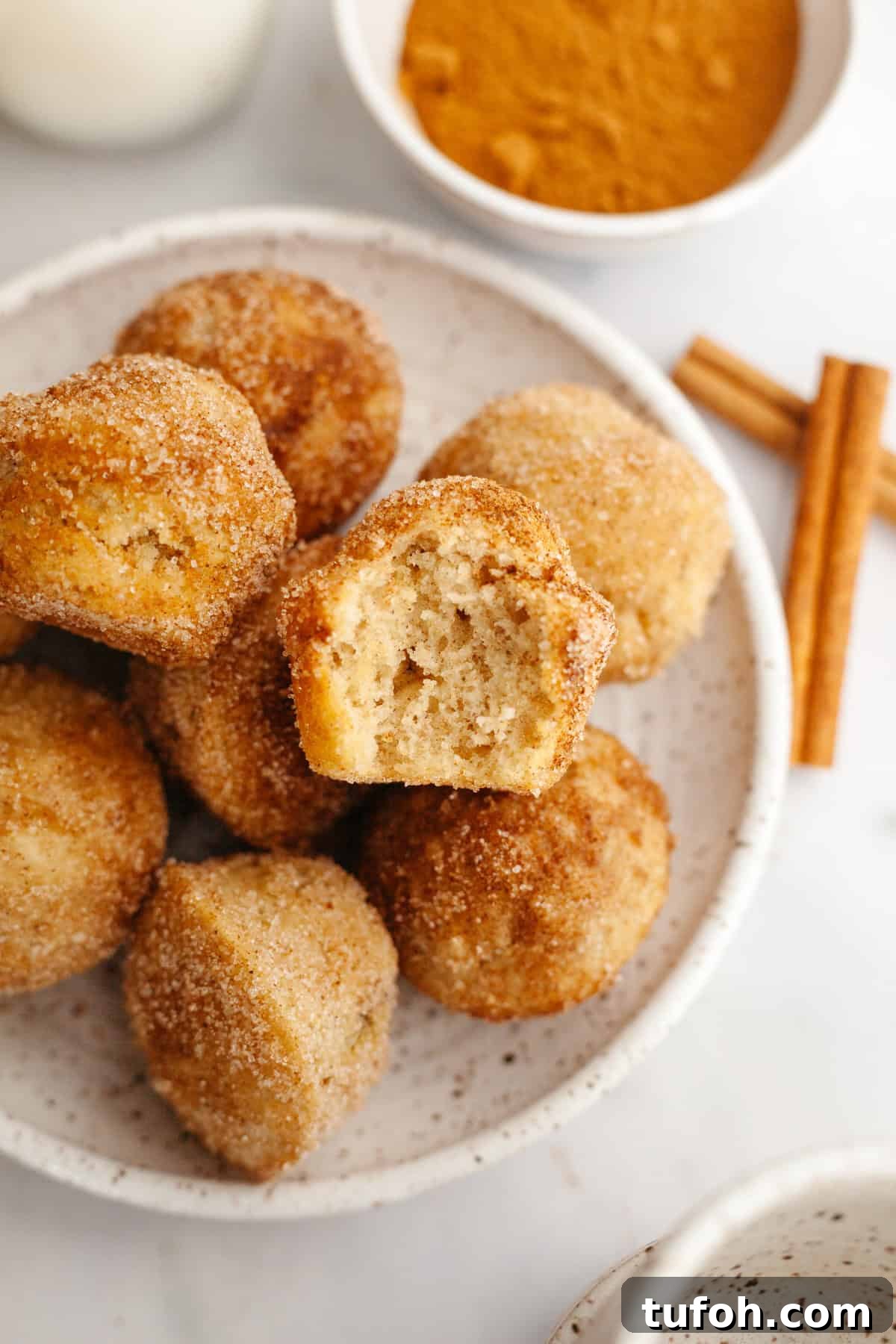 Cinnamon Mini Muffins Recipe: Quick, Soft & Flavorful 2 A plate full of cinnamon mini muffins, one has a bite taken out of it.