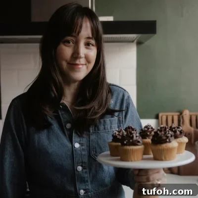 Cinnamon Mini Muffins Recipe: Quick, Soft & Flavorful 14 Ella from Alpine Ella is holding a cake stand with cupcakes on it.