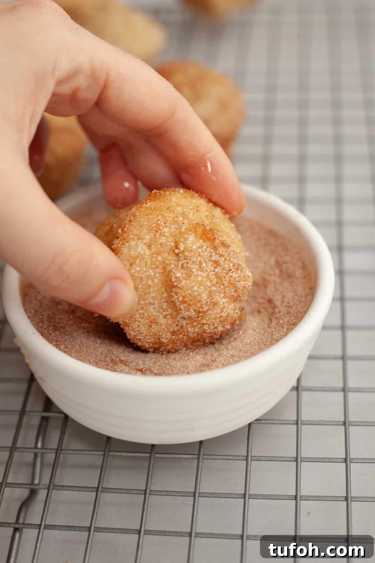 Cinnamon Mini Muffins Recipe: Quick, Soft & Flavorful 7 A hand rolling a mini muffin in cinnamon sugar.
