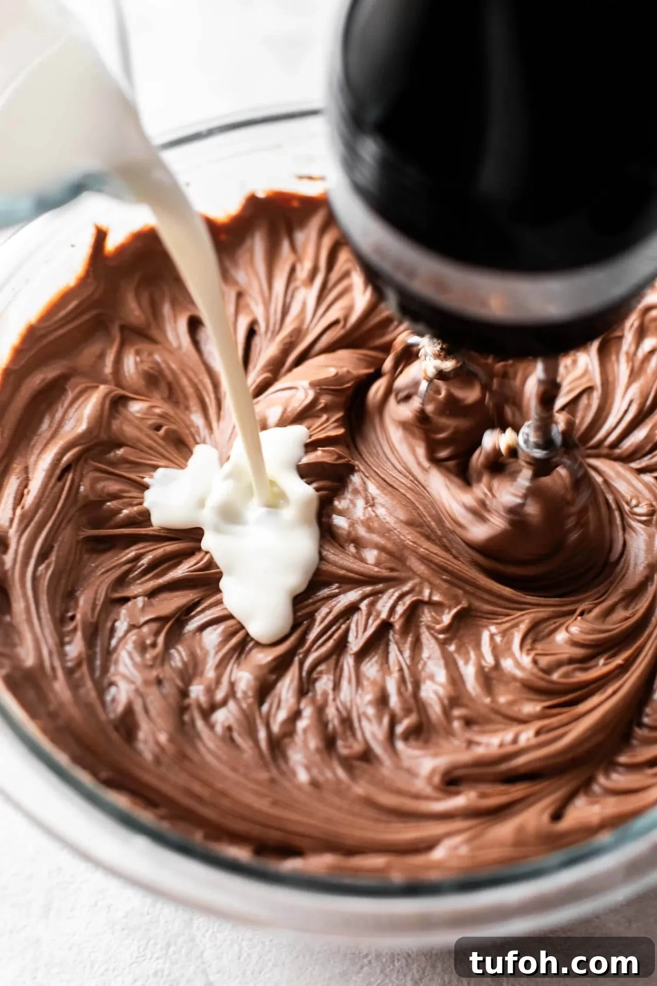 no bake chocolate cheesecake heavy cream being streamed into bowl of batter
