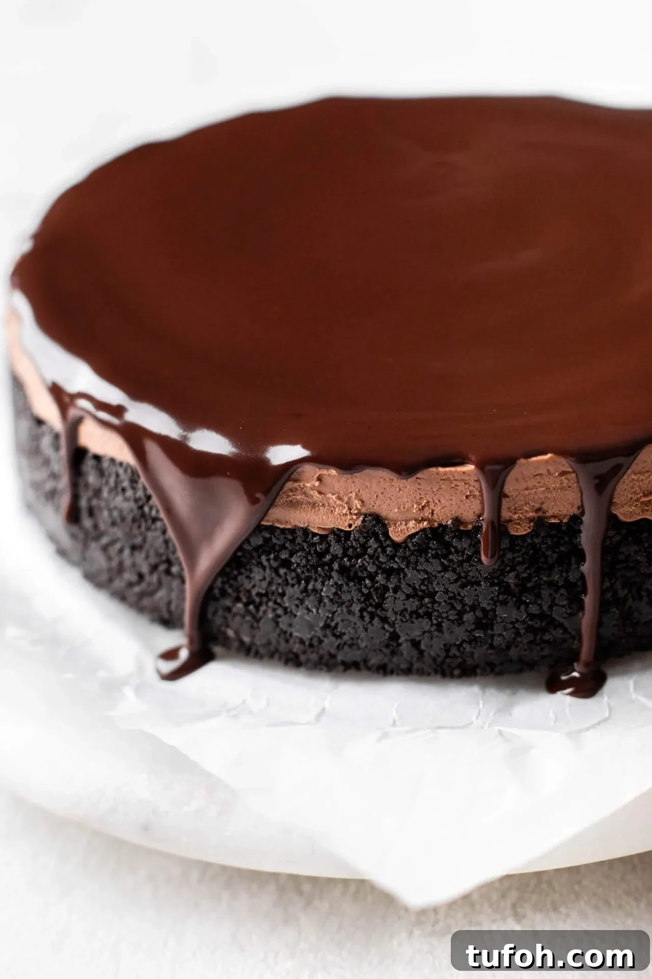no bake chocolate cheesecake removed from springform pan and topped with ganache