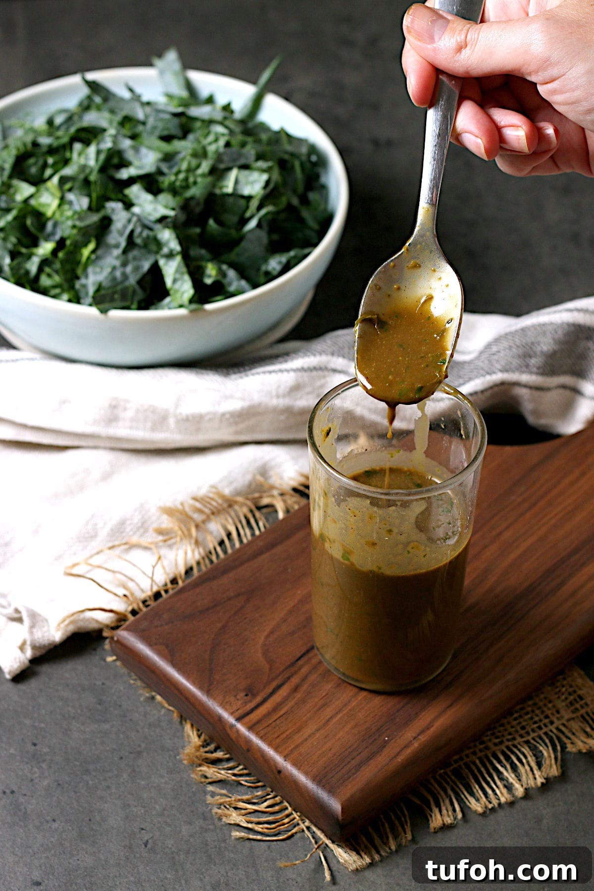 A hand holding a spoonful of Basil Balsamic Vinaigrette.