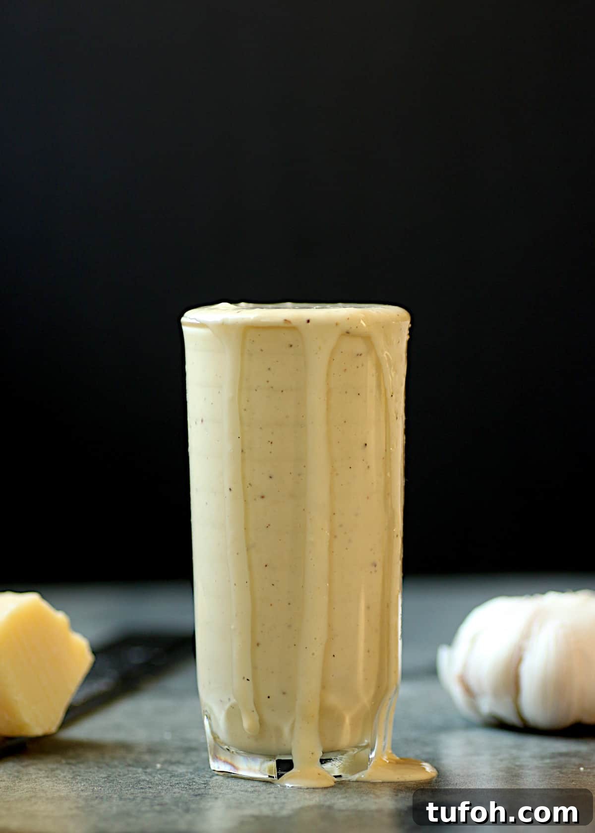 A glass filled to the brim with homemade caesar salad dressing.