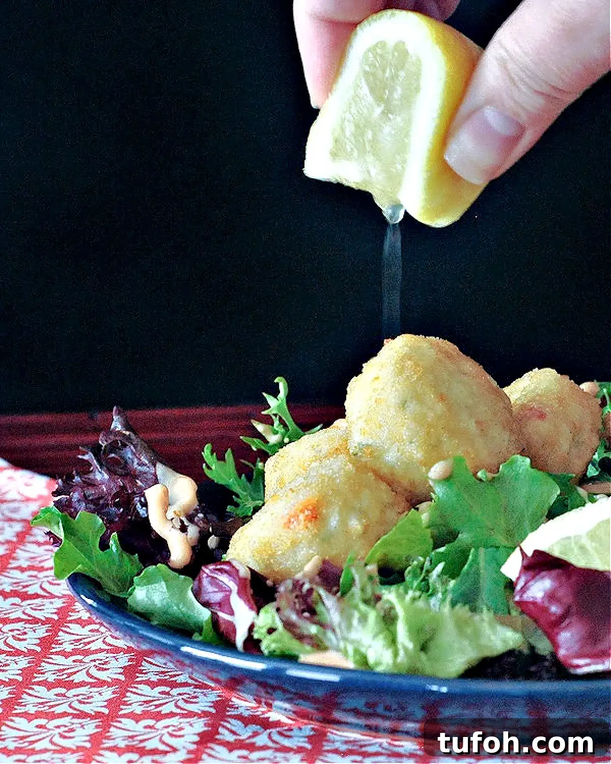 Vegan Thousand Island Dressing @spabettie #dairyfree #glutenfree #vegan #frysauce An entree salad of greens, crab cakes, and Thousand Island dressing; a hand squeezing a lemon over the salad.