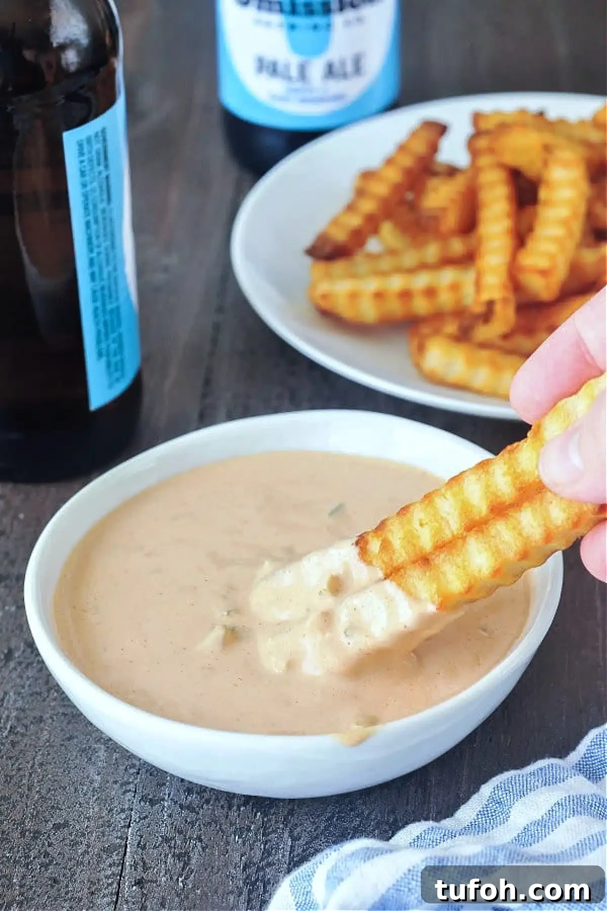 Vegan Thousand Island Dressing @spabettie #dairyfree #glutenfree #vegan #frysauce Krinkle cut French fries being dipped into a bowl of Thousand Island dressing, plate of fries and bottles of beer in background.