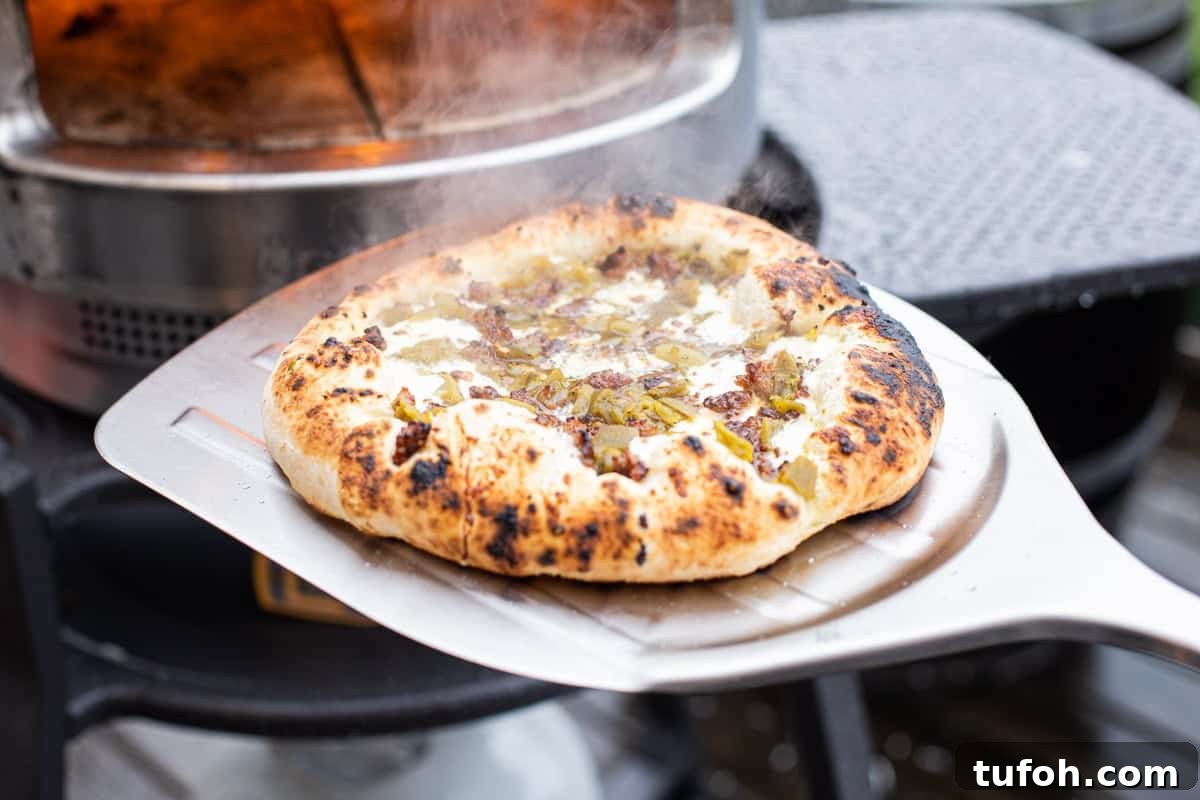 Green Chile and Chorizo Pizza Recipe with Melty Cheese 4 Removing green chile pizza from solo stove pi pizza oven.