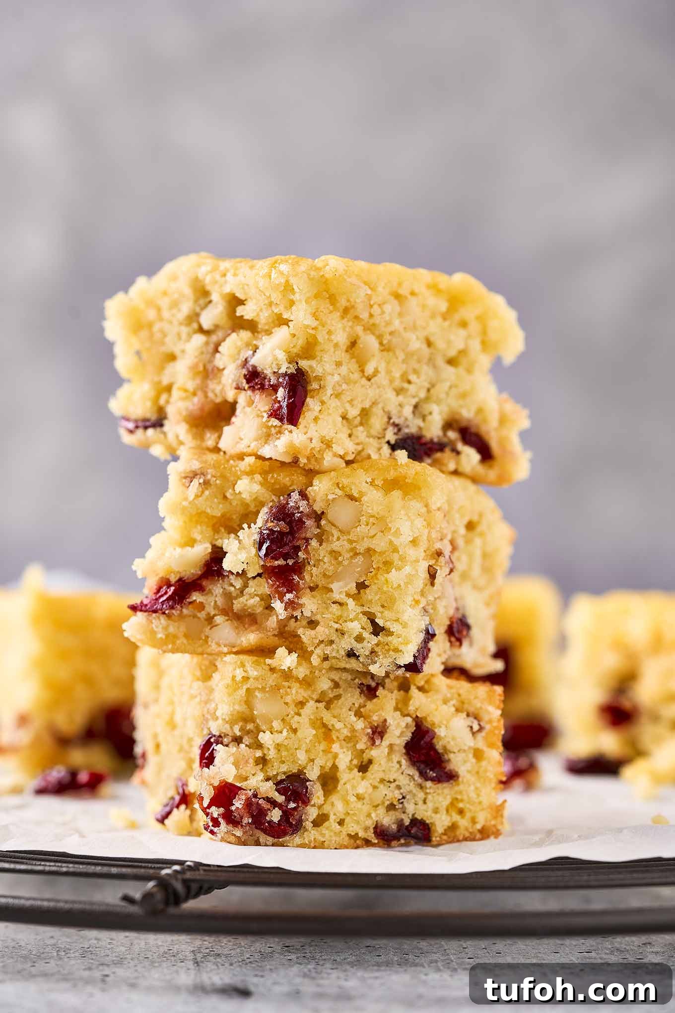 Cranberry Orange Bar Recipe — Tart, Chewy Holiday Dessert 2 Three cranberry bars stacked on a cooling rack, showing their dried cranberries, almonds, and orange zest.