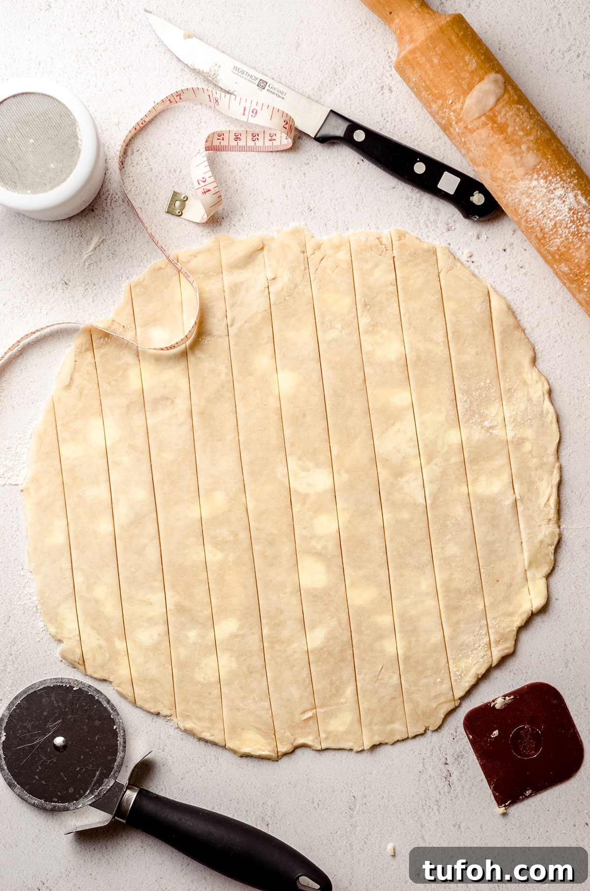 A circle of dough cut into pie dough strips.