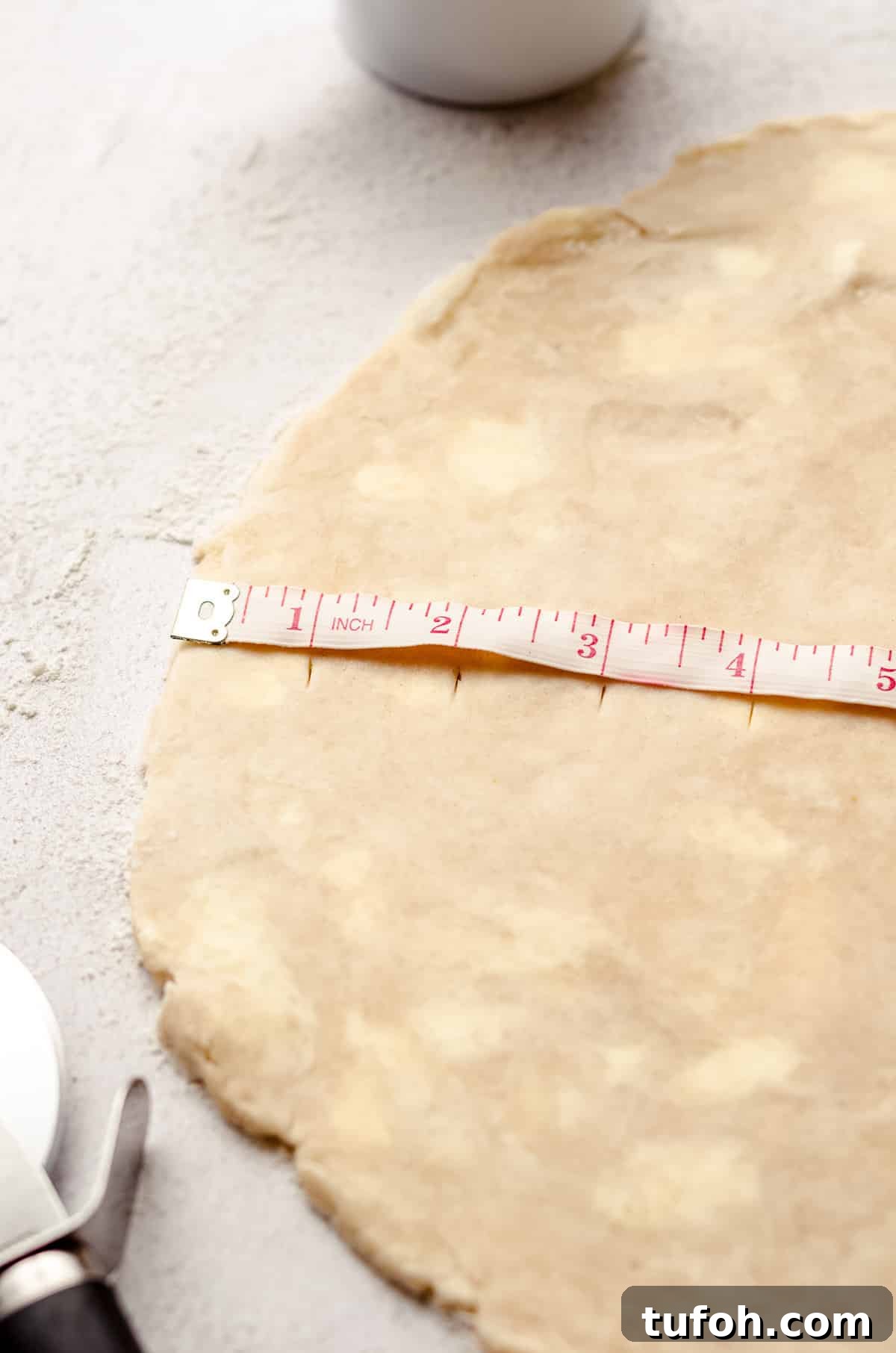 a tape measure on a disc of pie dough to cut lattice strips