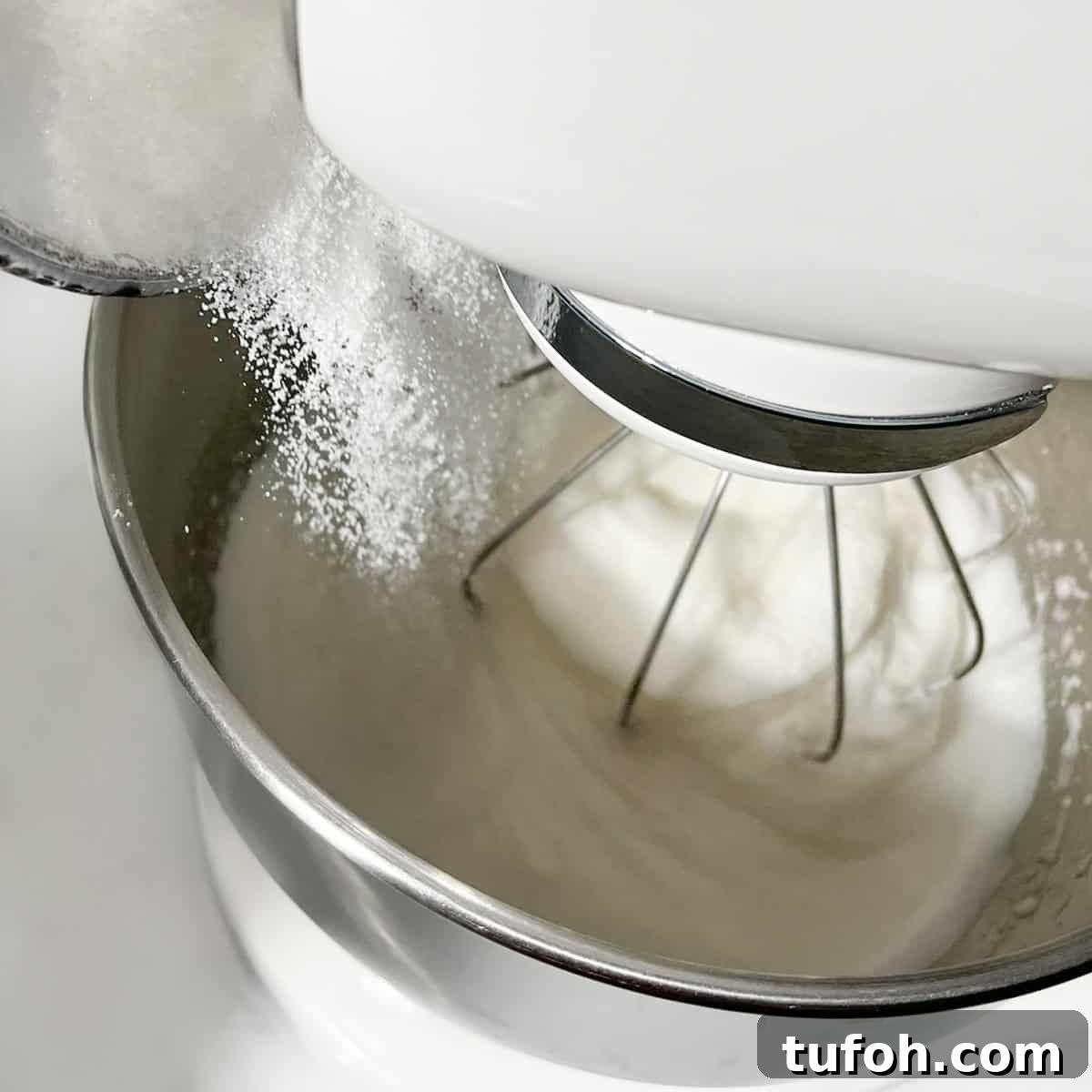Hertzoggies: South African Jam and Coconut Tartlets Recipe 13 Adding sugar to the meringue for the hertzoggies.