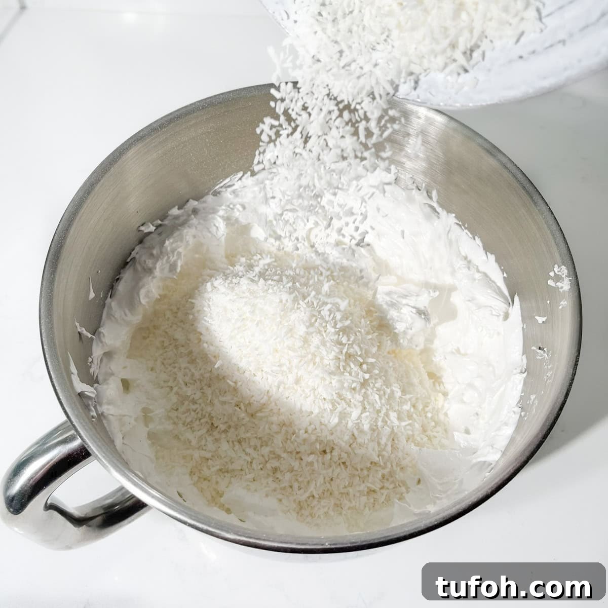 Hertzoggies: South African Jam and Coconut Tartlets Recipe 14 Adding coconut to meringue for the jam and coconut tartlets topping.