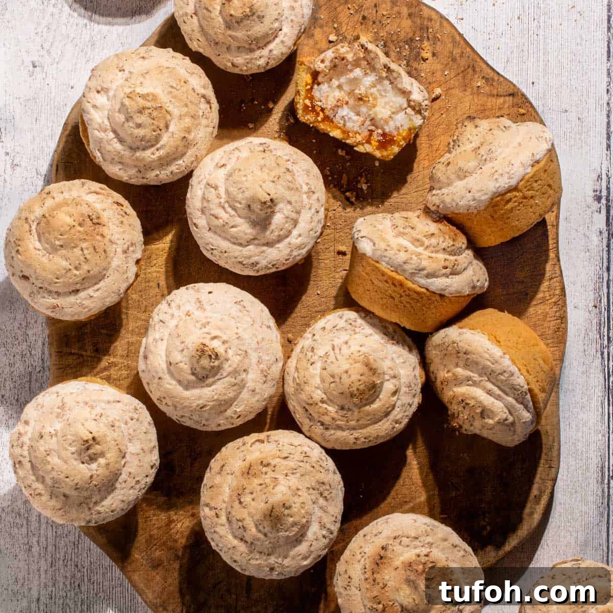 Hertzoggies: South African Jam and Coconut Tartlets Recipe 16 Hertzoggies on a wooden board on a white background.