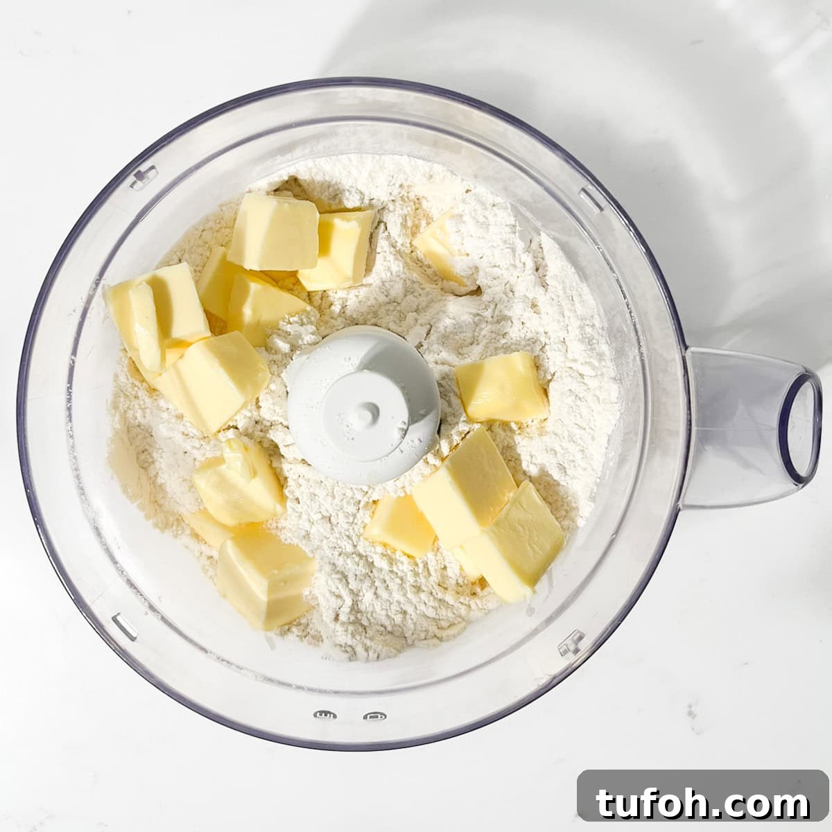 Hertzoggies: South African Jam and Coconut Tartlets Recipe 5 Adding cubed butter to flour in a food processer for the Hertzoggies.