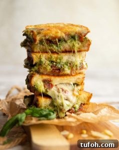 4 sandwich halves stacked on top of each other with pesto and cheese spilling out