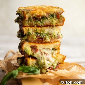 4 sandwich halves stacked on top of each other with pesto and cheese spilling out