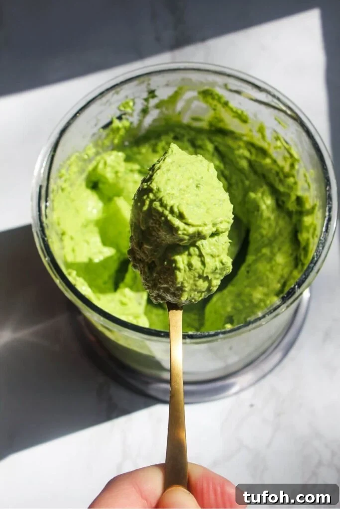 Hand holding up a small gold spoon with wild garlic butter on it.