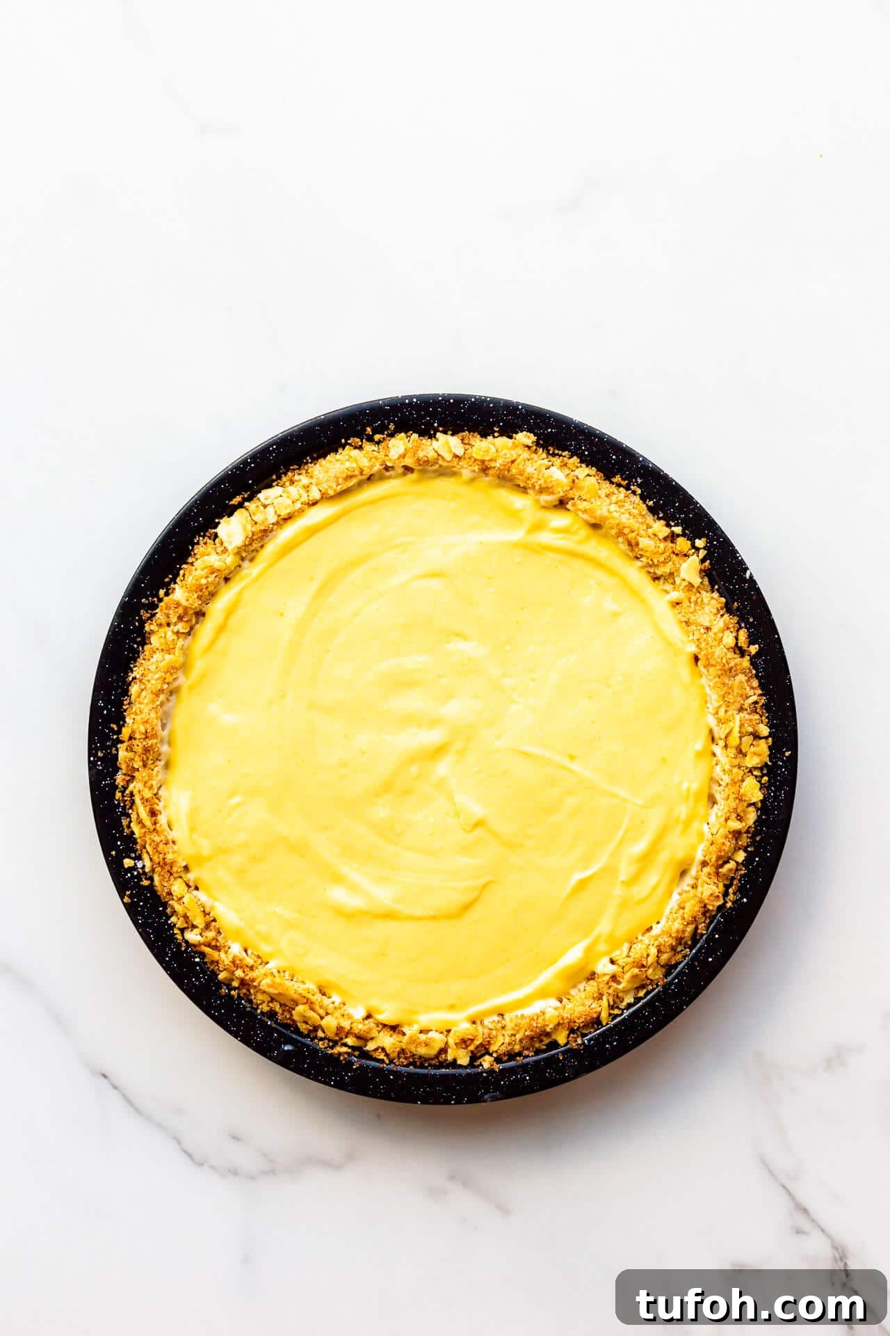 Zesty Orange Pie Recipe: Moist Citrus Tart with Fresh Orange Zest 7 Orange curd filled pie with saltine crust in black speckled pie plate.