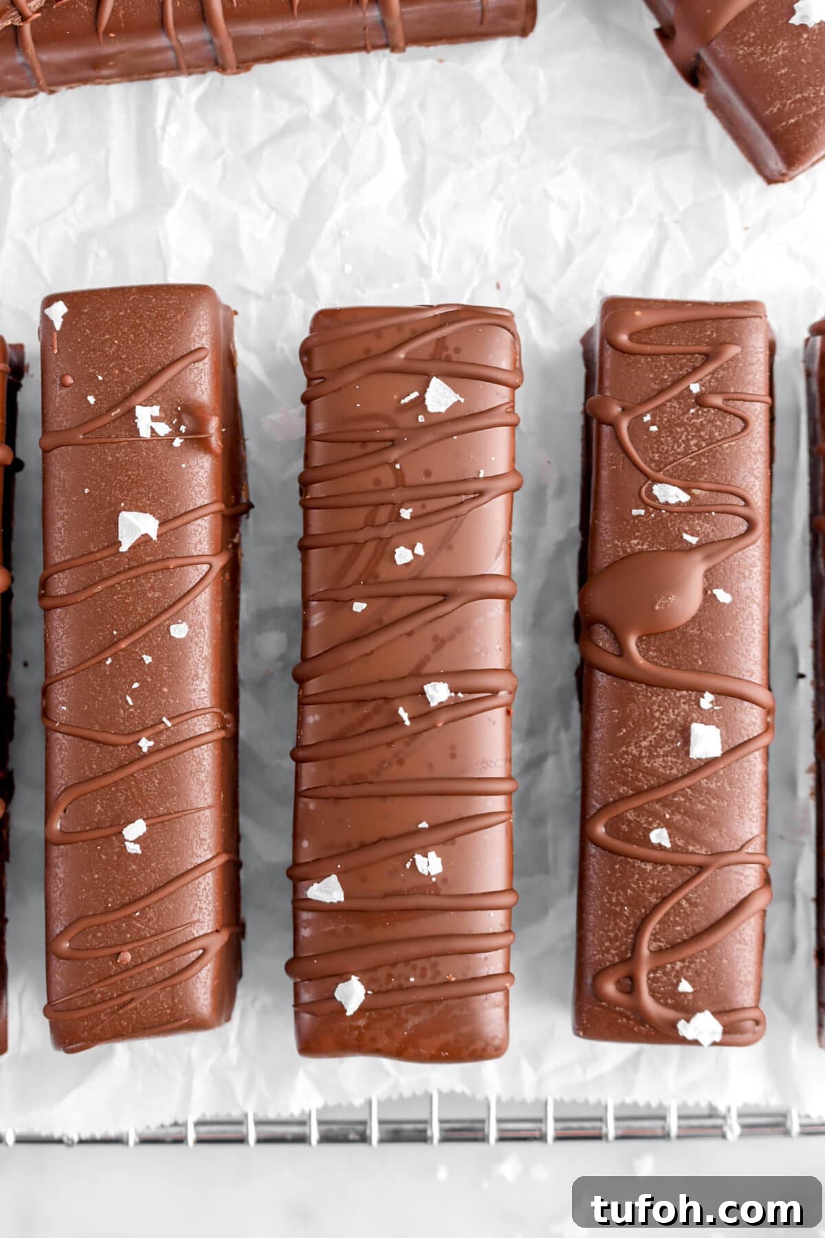 close up overhead shot of three chocolate coated candy bars with flaked salt