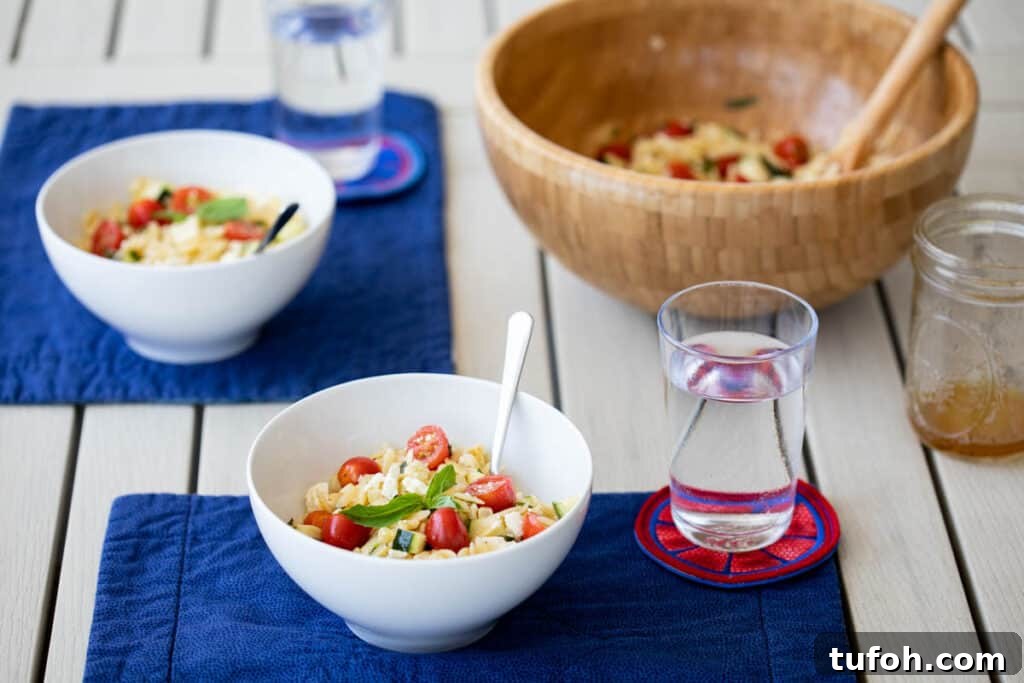 Summer Orzo (Risoni) Salad with Lemon & Fresh Herbs 9 bowls of summer orzo pasta salad with large salad bowl, glasses of water, and mason jar of vinaigrette