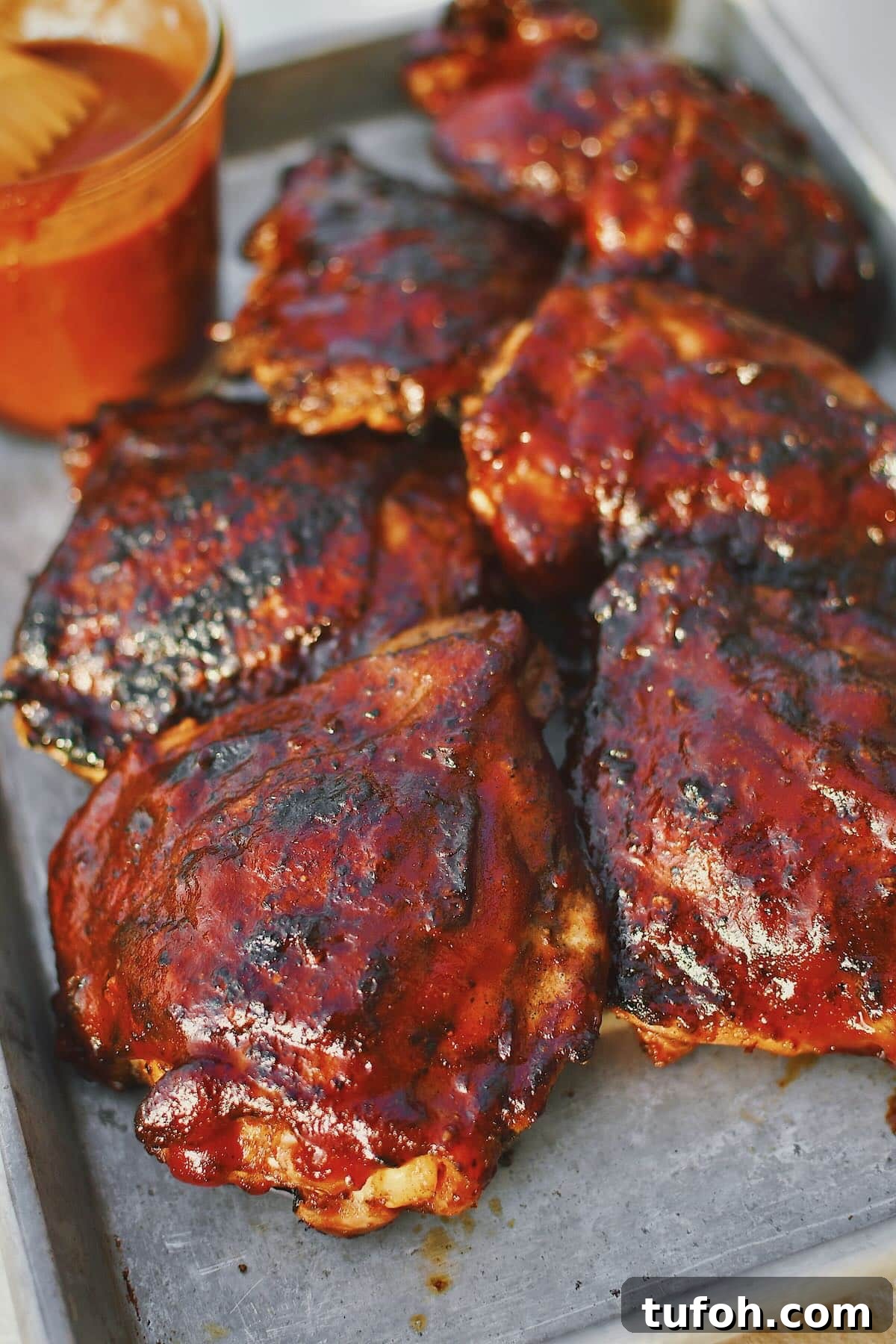 Juicy Grilled Chicken Thighs with Crispy Skin and Smoky Flavor 2 Grilled Chicken Thighs fresh off the grill and slathered in bbq sauce.
