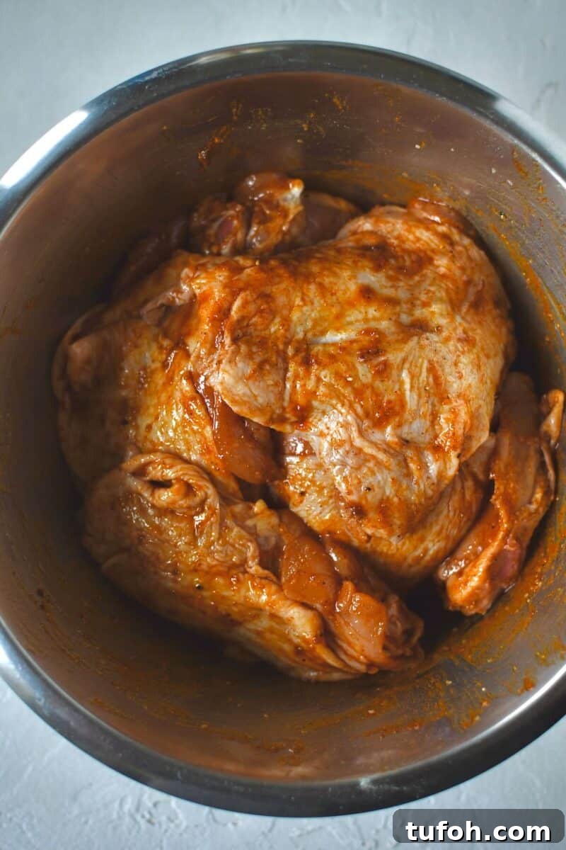 Juicy Grilled Chicken Thighs with Crispy Skin and Smoky Flavor 5 Chicken thighs in a bowl and tossed with the seasonings to coat.