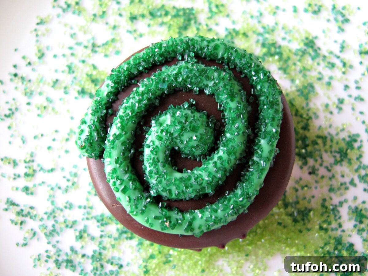 St. Patrick’s Day Chocolate-Covered Oreo Treats 5 Closeup showing green colored sugar on top of piped green candy coating swirl.