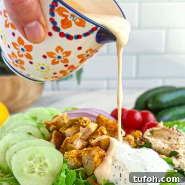 Creamy Tahini Dressing Recipe for Salads and Bowls 9 Pouring tahini dressing on a salad.