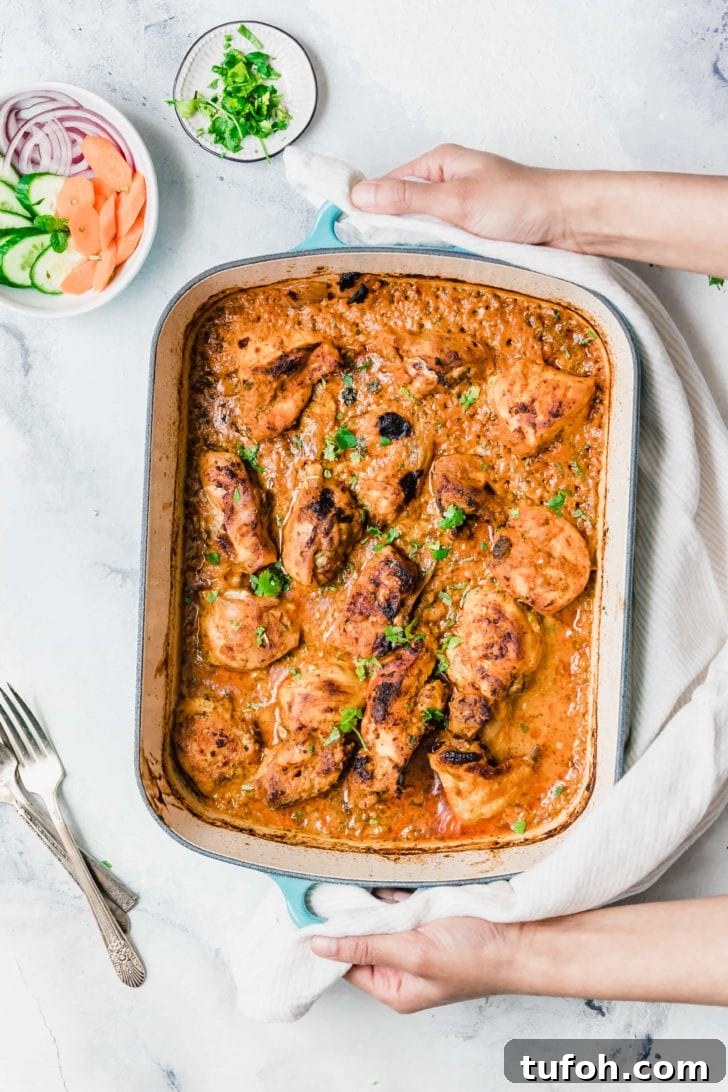 Oven-Baked Tandoori Chicken Curry Recipe 2 Holding a pan of Baked Tandoori Chicken Curry.